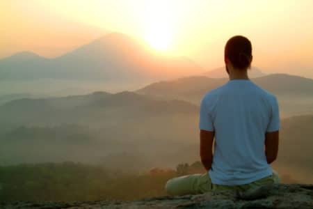 Man Meditating On An Overlook With View Of Mountains